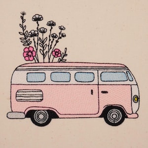 Könnte beinhalten: Ein rosafarbener Vintage-Van mit weißen Verzierungen und Fenstern, verziert mit rosa und weißen Blumen auf dem Dach.