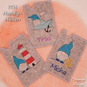 Puede incluir: Tres porta tarjetas de fieltro con diseños bordados. El primer porta tarjetas presenta un gnomo en un barco con un ancla y el nombre "Trixi". El segundo porta tarjetas presenta un gnomo de pie junto a un faro y el nombre "Micha". El tercer porta tarjetas presenta un gnomo sosteniendo un timón y el nombre "Micha".