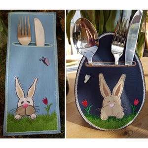 May include: Two embroidered felt place card holders featuring a bunny rabbit design. One is blue with a spoon and fork, the other is light blue with a knife and fork.
