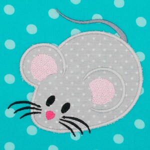 Könnte beinhalten: Gestickte graue Maus mit weißen Punkten, rosa Ohren und einer rosa Nase. Die Maus hat schwarze Augen und Schnurrhaare. Der Hintergrund ist ein türkisfarbener Stoff mit weißen Punkten. Geeignet für Kinderartikel.