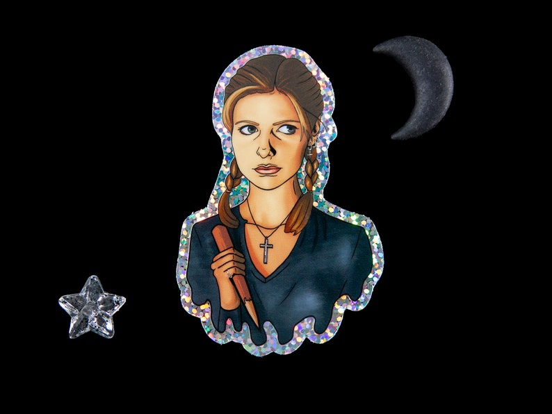 Buffy Summers sticker with glitter border and details. She is wearing a glittery cross and holding a wooden stake. There is a small star and half moon sitting next to the sticker.