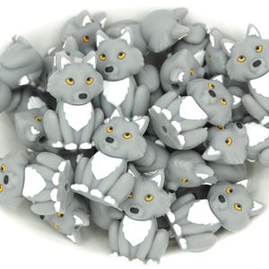 May include: A bowl filled with gray silicone wolf-shaped beads. The beads have white accents and gold eyes.
