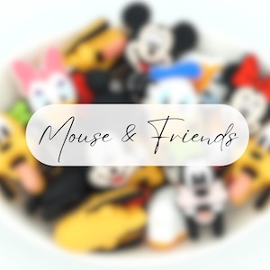 Puede incluir: Una colección de figuras de personajes coloridos, incluyendo Mickey Mouse, Minnie Mouse, Pato Donald, y otros, están dispuestos en un cuenco blanco. El texto "Mouse & Friends" está superpuesto en la imagen.