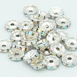 May include: A pile of silver-toned metal bead caps with iridescent rhinestones around the edge.