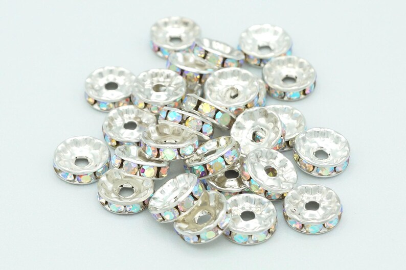 May include: A pile of silver-toned metal bead caps with iridescent rhinestones around the edge.