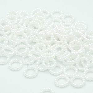 May include: A large pile of white pearl rings. The rings are made of small, round pearls that are strung together to form a circle.