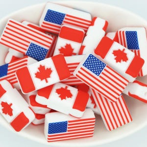 May include: A bowl filled with red, white and blue silicone charms shaped like the American and Canadian flags.