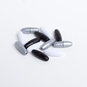 May include: A group of 14 plastic cord ends in black, white, and silver. The cord ends are oval shaped and have a small hole in the centre.