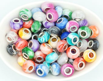 May include: A collection of colorful glass beads with silver-toned metal cores. The beads are in various colors, including pink, blue, green, purple, and orange, and are displayed in a white bowl. These beads are ideal for jewelry making.