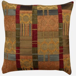 May include: A decorative throw pillow with a patchwork design featuring various shades of brown, red, and green. The pillow has a geometric pattern with swirls and stripes.