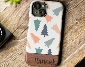 Könnte beinhalten: Eine weiße Handyhülle mit einem Muster aus bunten Weihnachtsbäumen. Der untere Teil der Hülle ist aus Holzimitat mit dem eingravierten Namen "Hannah".