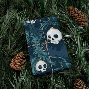 May include: A dark blue wrapping paper with a repeating pattern of white skull ornaments hanging from pine branches. The paper is tied with twine.
