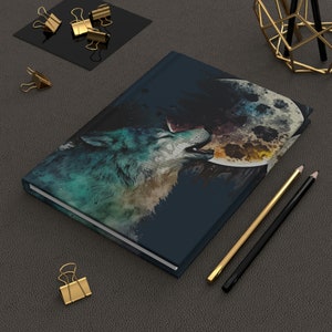 May include: A dark blue notebook with a watercolor illustration of a wolf howling at a full moon. The moon is painted in shades of yellow, orange, and blue.