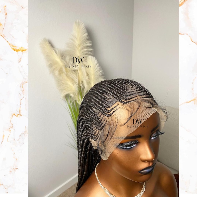 May include: A black braided wig with a lace front is displayed on a mannequin head. The wig features intricate cornrow braids and a natural-looking hairline. The mannequin has dark skin and is wearing a necklace. The brand name "DW DAINTY WIGS" is visible.