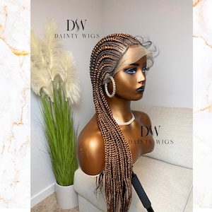 May include: A brown and blonde braided wig with a lace front. The wig is styled in a long, straight style. The wig is on a mannequin head.