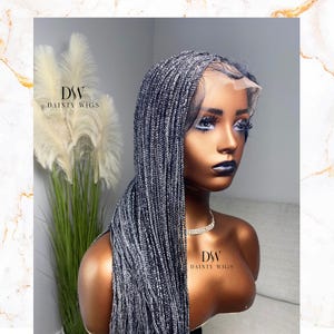 May include: A silver grey braided wig with a lace front. The wig is styled in long, straight braids. The wig is on a mannequin head.