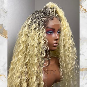 May include: A blonde wig with a braided crown and long, curly hair. The wig is styled on a mannequin head with makeup. The text "DAINTY HAIR" is visible on the mannequin.