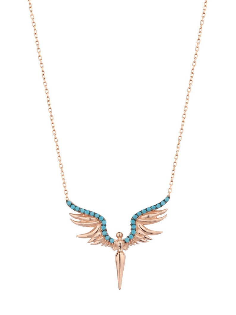 May include: A rose gold necklace with a turquoise stone angel wing pendant. The wings are detailed with small turquoise stones and the pendant is shaped like a pointed arrow.