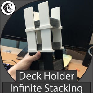 May include: A white and black deck holder with the text "Deck Holder Infinite Stacking". The holder is designed to hold multiple decks of cards. The holder is made of white and black plastic and has a multi-tiered design.