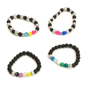 以下が含まれることがあります： 銀色のビーズとカラフルな宝石のアクセントが付いた、溶岩岩のブレスレット4本。各ブレスレットは、宝石の色使いが異なります。