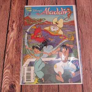 May include: A comic book cover featuring Aladdin and Jasmine from Disney's Aladdin. The cover is illustrated in a cartoon style and features the characters flying on a magic carpet. The title of the comic is "Disney's Aladdin: Rugged Flight!"