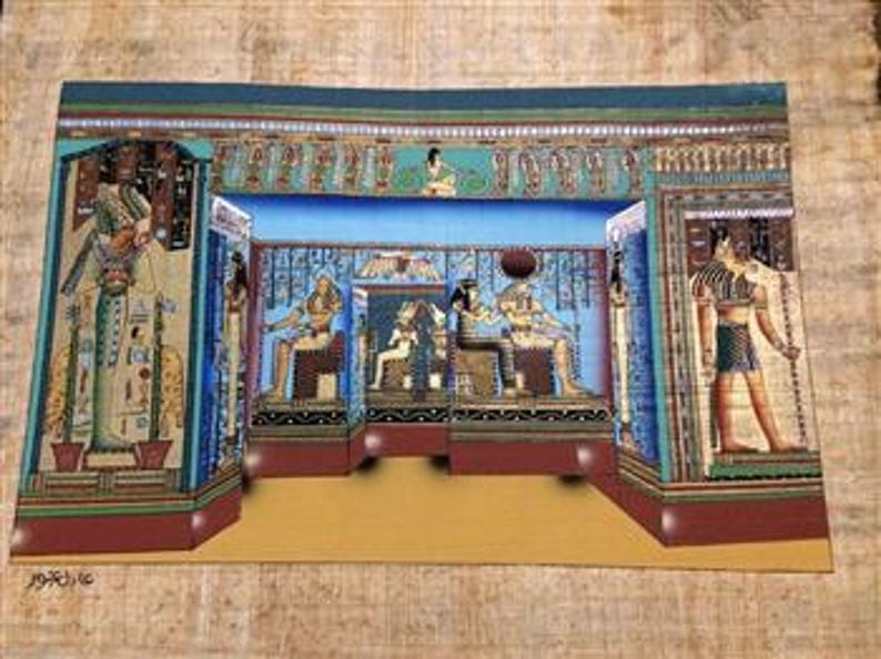 May include: A colorful painting on papyrus depicting an ancient Egyptian scene. The artwork features pharaohs, hieroglyphs, and intricate architectural details in shades of blue, gold, and brown. The painting is rectangular and appears to be displayed on a textured surface.