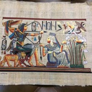May include: A colorful papyrus painting depicting an ancient Egyptian scene. The artwork features figures with detailed clothing and accessories, including a bow and arrow, set against a backdrop of hieroglyphs and birds. The painting is on a textured, beige papyrus sheet.