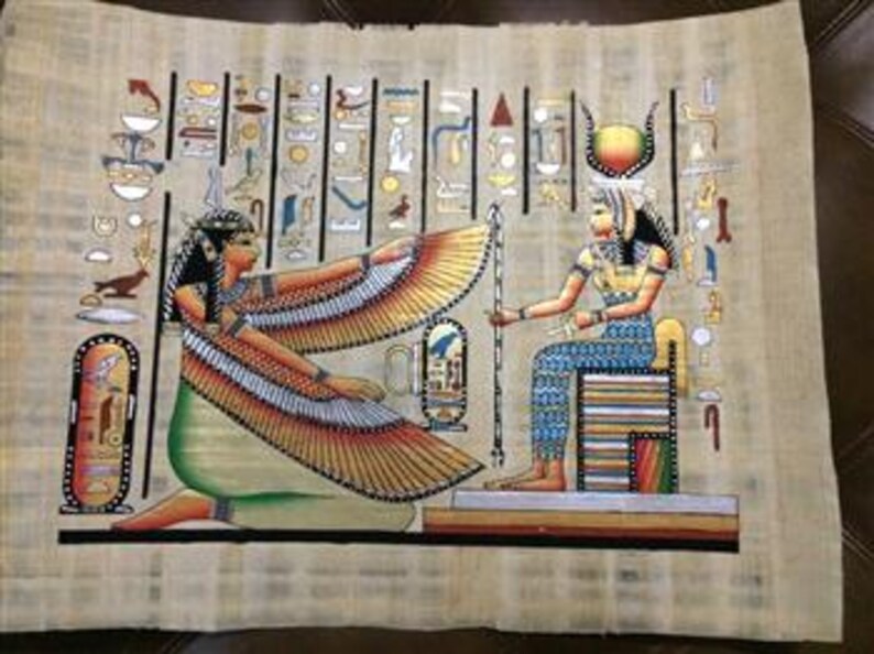 May include: A papyrus painting depicting two figures in ancient Egyptian attire. One figure kneels with outstretched, detailed wings, while the other sits on a throne. The artwork features hieroglyphs and vibrant colors, including gold, blue, and green.
