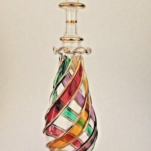 May include: A clear glass bottle with a gold-rimmed stopper and a swirling design of red, purple, green, and yellow glass.