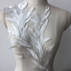 May include: White floral lace applique with a delicate leaf design. The lace is on a sheer mesh background and is perfect for adding a touch of elegance to any garment.