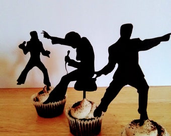 May include: Three black silhouette cupcake toppers of singers with microphones, each placed on top of a chocolate cupcake with white frosting.