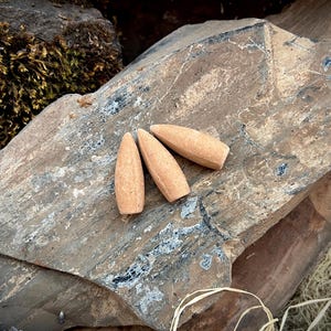 May include: Three brown incense cones arranged in a triangular shape on a rough, gray rock surface.