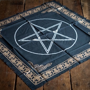 May include: A black cloth altar cloth with a white pentagram inside a circle. The cloth has a gold-colored border with a Celtic knot design.