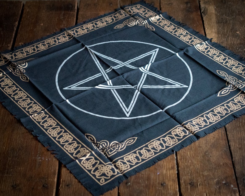 Pu&ograve; includere: Un panno da altare nero con un pentagramma bianco all'interno di un cerchio. Il panno ha un bordo dorato con un motivo a nodo celtico.