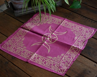 May include: A pink silk altar cloth with a gold triple moon and pentacle design. The border is a gold Celtic knot pattern.