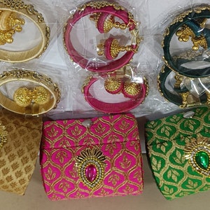 May include: Six pairs of colorful silk thread bangles with matching earrings. The bangles are decorated with gold trim and embellishments. The earrings are also decorated with gold and have a dangling design.