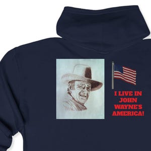 Può includere: Felpa con cappuccio blu navy con un rettangolo bianco sul retro che presenta un disegno di John Wayne con un cappello da cowboy e il testo "I live in John Wayne's America!" con una bandiera americana sullo sfondo.