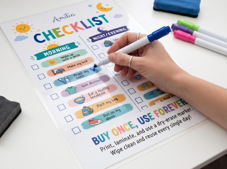 A person uses a blue dry-erase marker to check off an item on a laminated kids morning and night routine checklist sheet.
