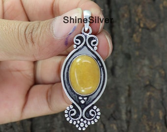 May include: A silver pendant with an oval, yellow gemstone. The pendant has a decorative, openwork design around the stone and a small loop at the top for a chain. The text "ShineSilver" is visible.