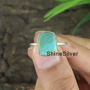 May include: A turquoise gemstone ring set in sterling silver. The ring features a square-shaped stone with a light blue and green color.