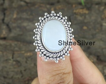 Può includere: Un anello d'argento con una pietra ovale azzurra. La pietra è incastonata in una montatura d'argento dettagliata con un bordo a forma di corda e piccoli accenti di perline. Il testo "ShineSilver" è visibile sull'anello.