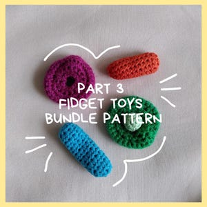 Può includere: Una collezione di quattro colorati giocattoli fidget all'uncinetto. I giocattoli includono un cerchio viola, un cilindro arancione, un cilindro blu e un cerchio verde con un centro verde chiaro. È presente anche il testo "PART 3 FIDGET TOYS BUNDLE PATTERN".