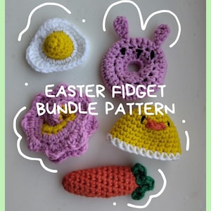 May include: A collection of handmade crochet Easter-themed fidget toys. Includes a fried egg, a purple bunny, a pink flower, a yellow chick, and an orange carrot with green leaves. The text "EASTER FIDGET BUNDLE PATTERN" is also visible.