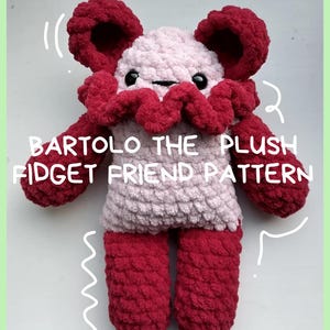 May include: A handmade plush toy in shades of pink and burgundy. The toy has a round head with large, floppy ears and a ruffled collar. The text "BARTOLO THE PLUSH FIDGET FRIEND PATTERN" is displayed on the front.