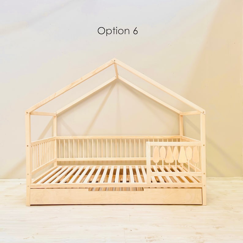 May include: A wooden house-shaped bed frame with a slatted mattress and a pull-out drawer. The bed frame has a decorative railing with tree-shaped cutouts. Option 6 is written above the bed frame.