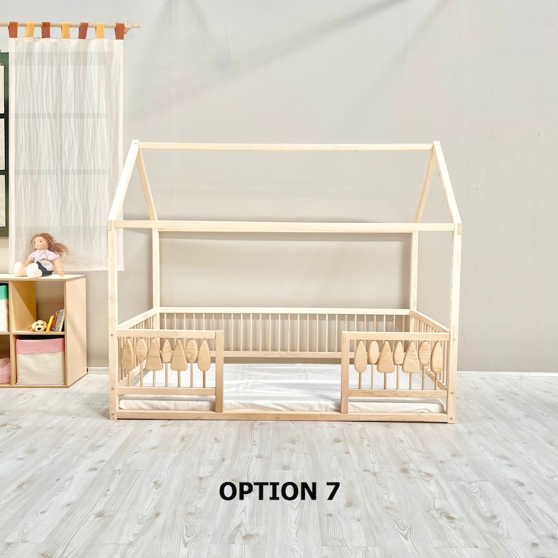 May include: A wooden house-shaped bed frame with a white mattress and a safety rail on each side. The safety rails have wooden cutouts shaped like trees. The text "OPTION 7" is printed below the bed frame.