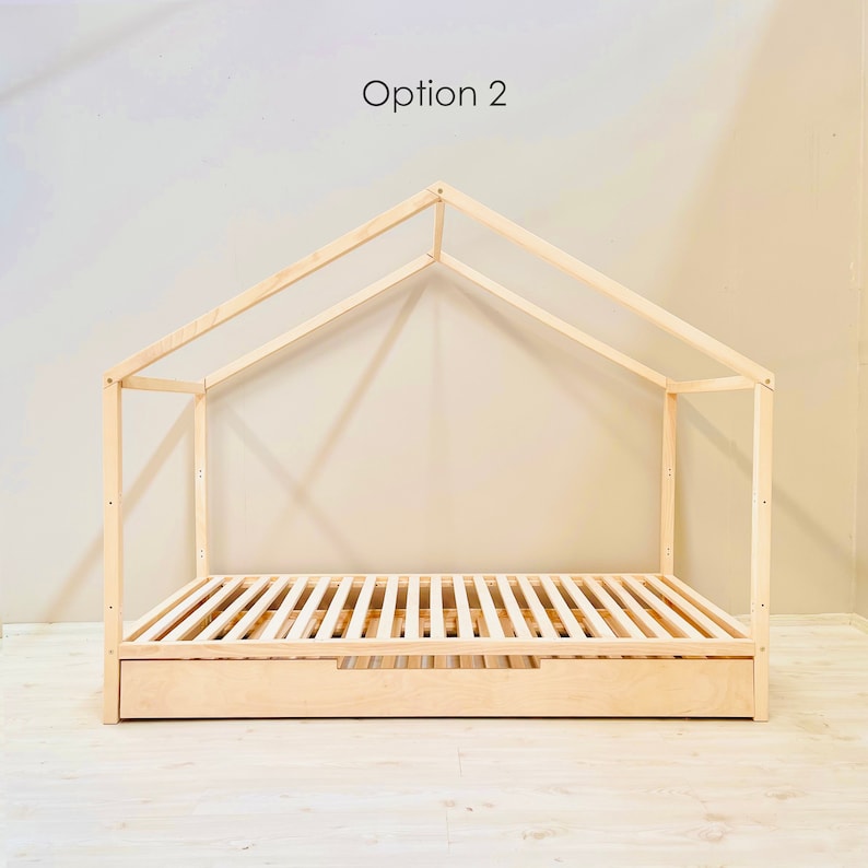 May include: A wooden bed frame with a house-shaped canopy. The bed has a slatted base and a drawer underneath. The text "Option 2" is visible in the image.