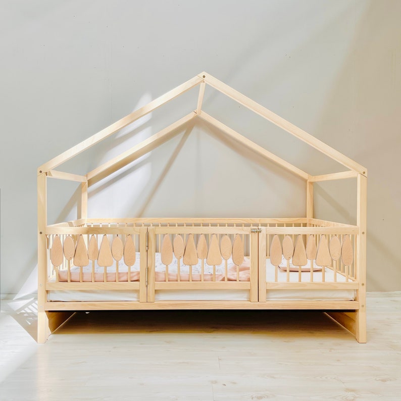 May include: A wooden toddler bed with a house-shaped frame and a removable safety rail. The bed has a light wood finish and a white mattress.