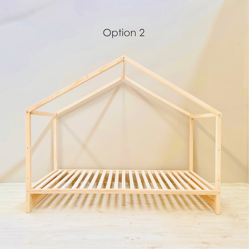 May include: A wooden bed frame with a house-shaped canopy. The frame is made of natural wood and has a slatted base. The canopy is open on all sides and has a simple, modern design.