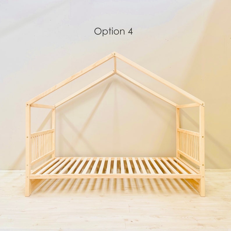 May include: A wooden bed frame with a house-shaped canopy. The frame is made of natural wood and has a slatted headboard and footboard. The canopy is made of two pieces of wood that meet at a point in the center. The bed frame is sitting on a light wood floor.